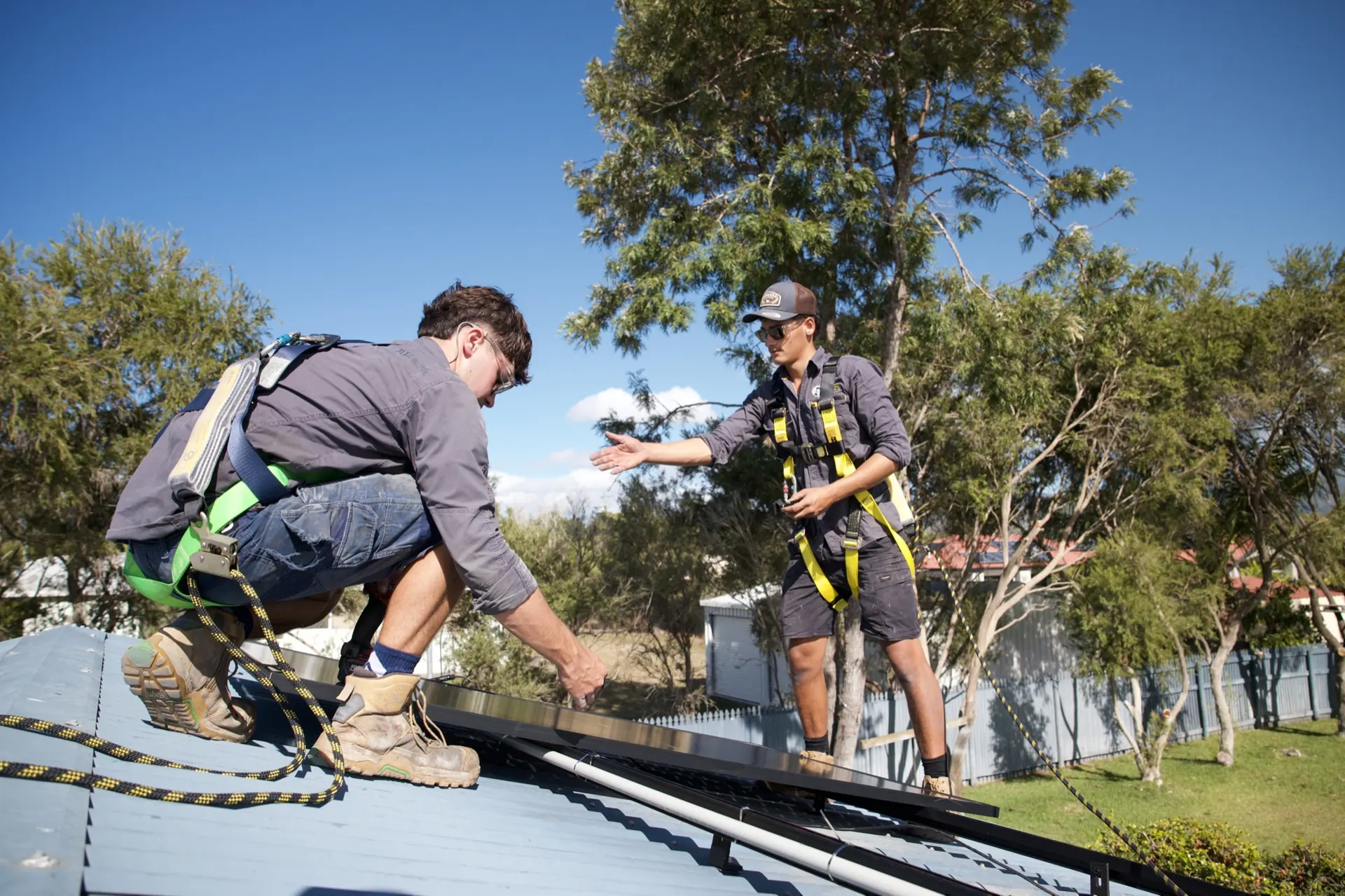 Two installers, both in harnesses, laying the new panels.