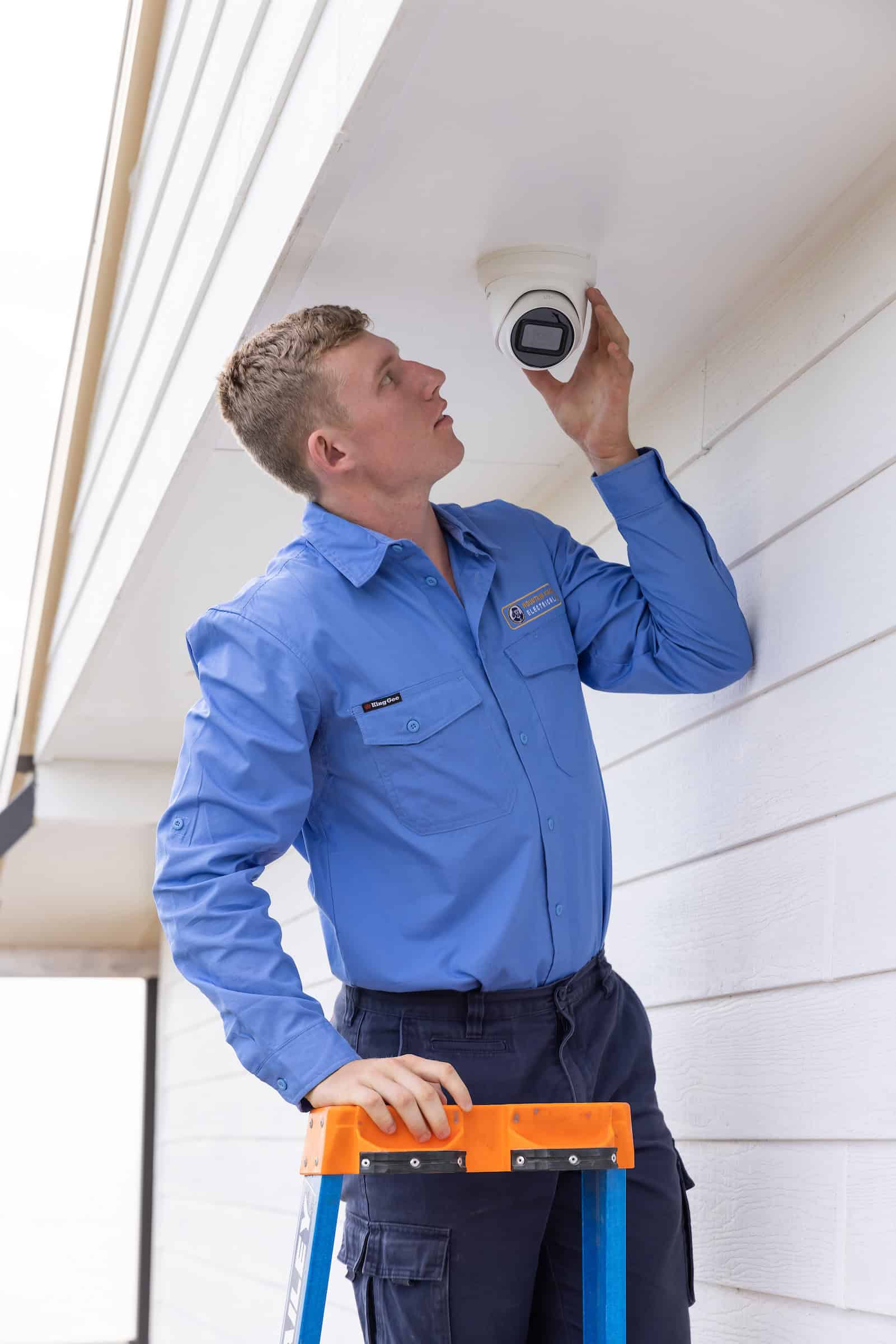 An electrician installing security cameras.