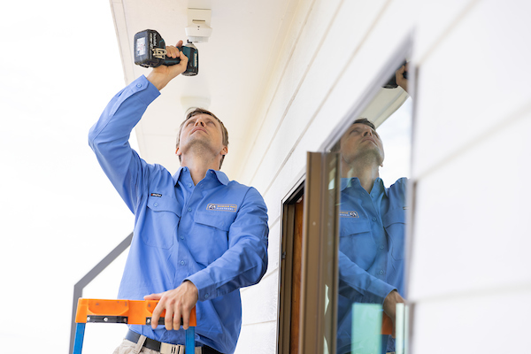 A professional electrician installing a home security system.