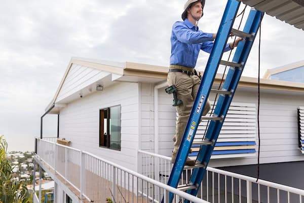 A friendly Mountain Man electrician climbing a ladder.