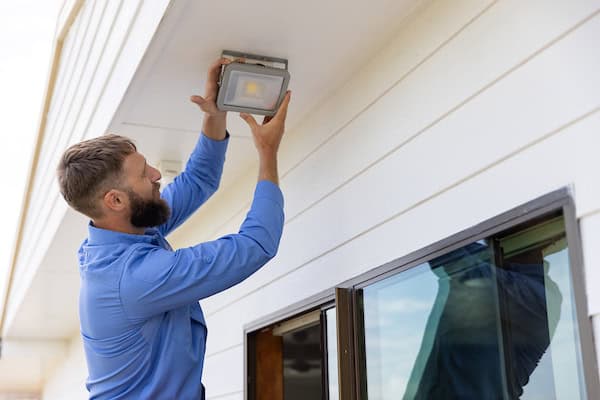 A Mountain Man Electrician installing security lighting on a building exterior.